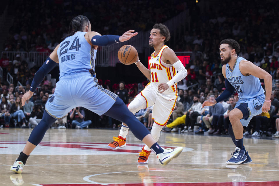 Atlanta Hawks guard Trae Young looks to pass between Memphis Grizzlies forward Dillon Brooks and guard Tyus Jones during the second half of an NBA basketball game, Sunday, March 26, 2023, in Atlanta. (AP Photo/Hakim Wright Sr.)