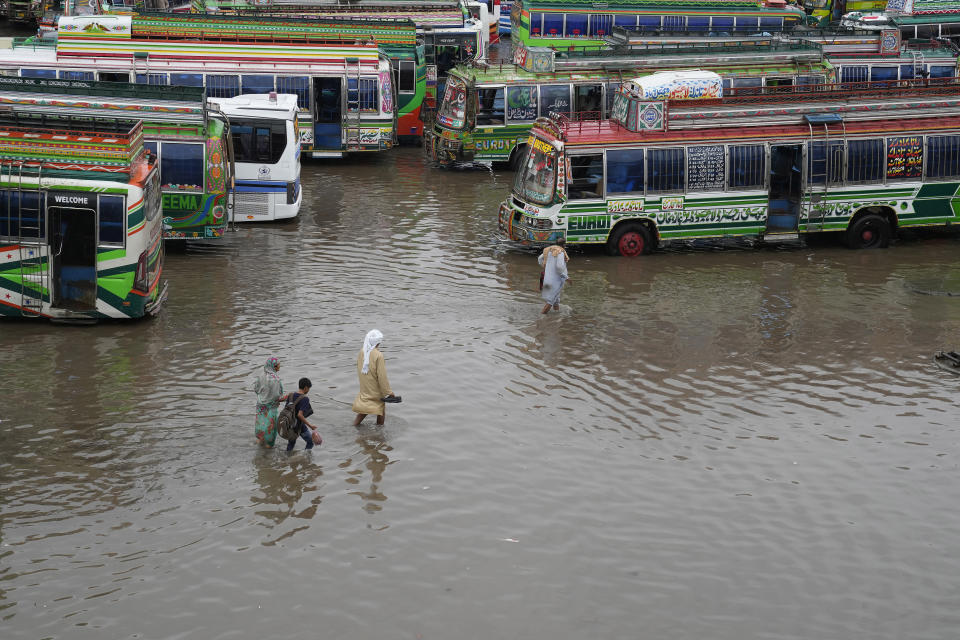 Passengers wade through a flooded bus terminal caused by heavy monsoon rainfall in Lahore, Pakistan, Wednesday, July 5, 2023. Officials say heavy monsoon rains have lashed across Pakistan, killing a number of people. (AP Photo/K.M. Chaudary)