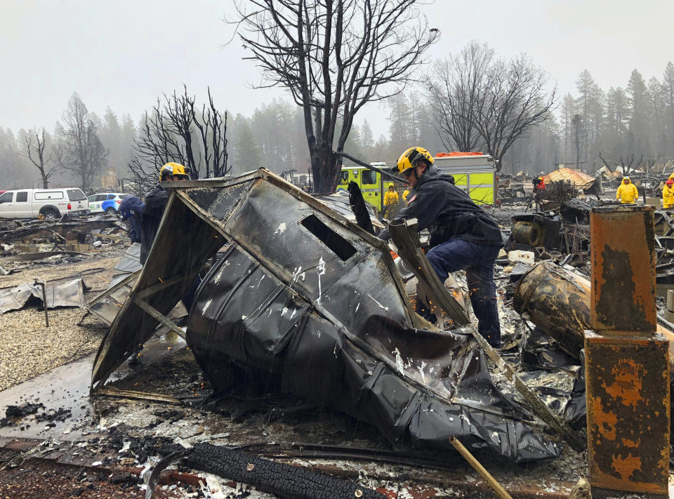 Steven McKnight, right, and Daniel Hansen saw through large pieces of sheet metal so they can be moved to allow cadaver dogs to search beneath them for signs of human remains at a mobile home park in Paradise, Calif., Friday, Nov. 23, 2018. They said the mobile home park had already been hand searched, so they were re-examining it with search dogs. (AP Photo/Kathleen Ronayne)