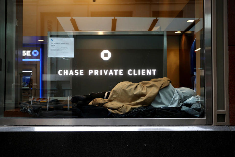 A homeless man sleeps in a closed Chase bank branch on a nearly deserted Wall Street in the financial district in lower Manhattan during the outbreak of the coronavirus disease (COVID-19) in New York City, New York, U.S., April 3, 2020. REUTERS/Mike Segar     TPX IMAGES OF THE DAY