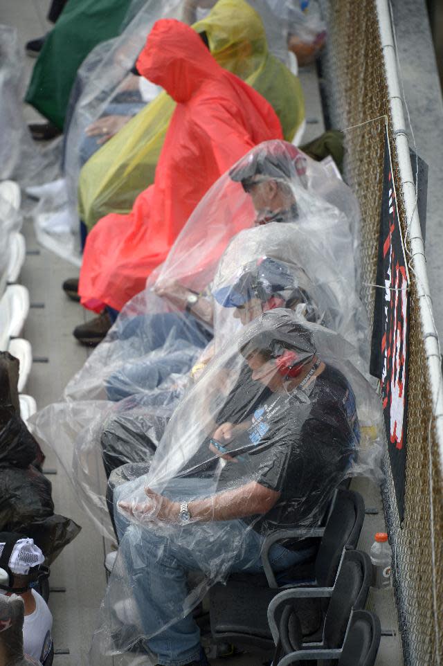 Race fans take cover from the rain in the stands during the NASCAR Daytona 500 auto race at Daytona International Speedway, Sunday, Feb. 23, 2014, in Daytona Beach, Fla. (AP Photo/Phelan M. Ebenhack)