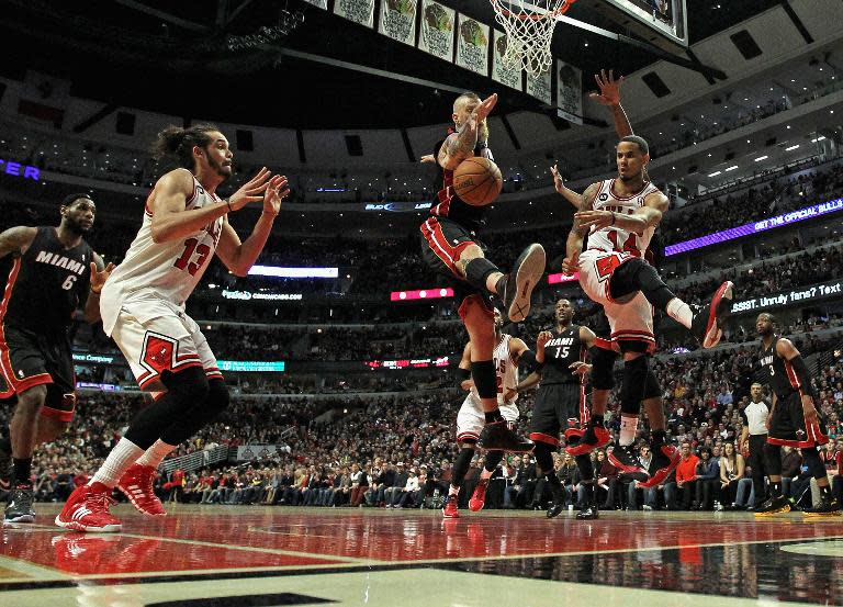 D.J. Augustin of the Chicago Bulls passes to teammate Joakim Noah around Chris Anderson of the Miami Heat at the United Center on March 9, 2014 in Chicago, Illinois