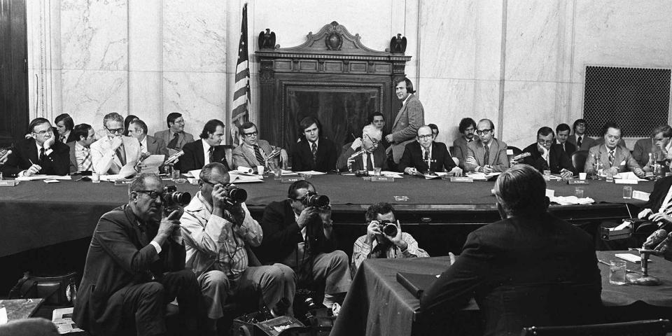 A black and white photo of lawmakers during the Watergate Committee hearings.