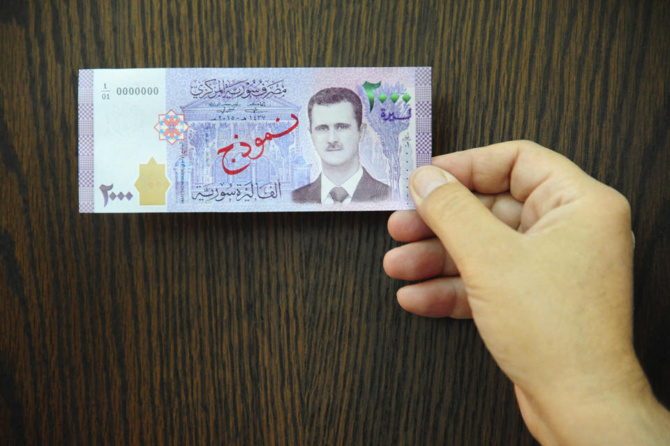 FILE - In this July 2, 2017 file photo released by the Syrian official news agency SANA, a man displays a new bank note of 2,000 Syrian Lira, during a press conference for the Syria's Central Bank Governor, in Damascus, Syria. In Syria nowadays, there is an impending fear that all doors are closing. After nearly a decade of war, the country is crumbling under the weight of years-long western sanctions, government corruption and infighting, a pandemic and an economic downslide made worse by the financial crisis in Lebanon, Syria's main link with the outside world. (SANA via AP, File)