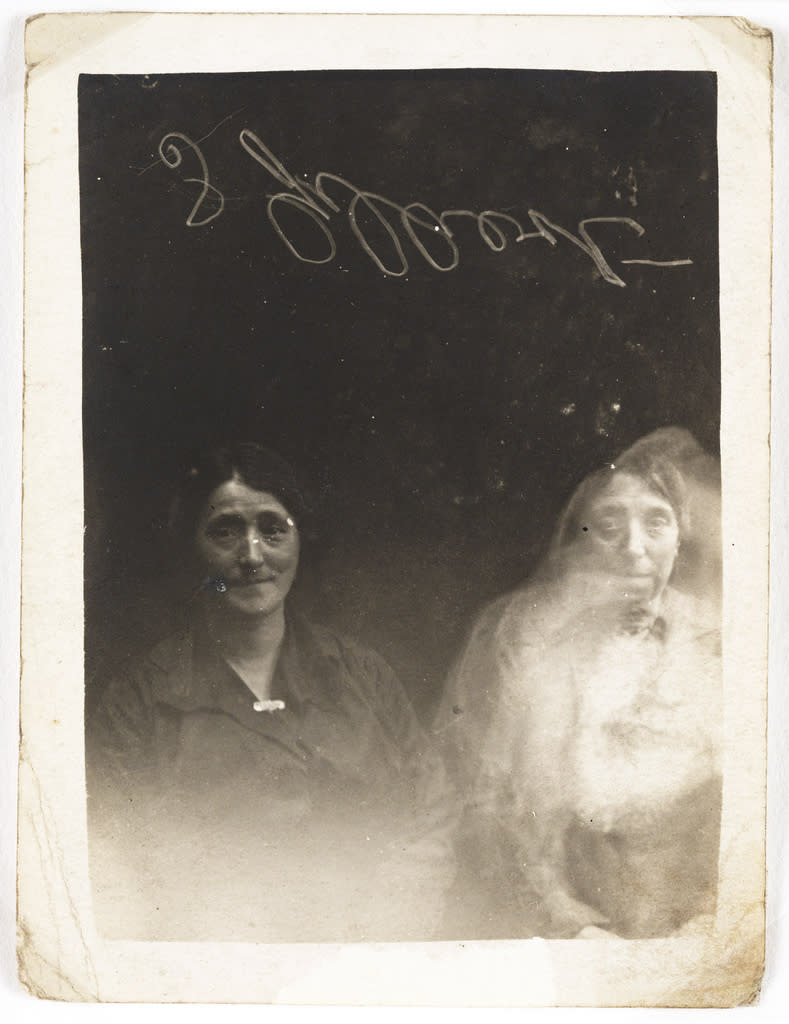 The face of a young woman appears over the woman on the right of the photograph, c. 1920. The reverse of the photograph reads: "Why is the child always pushing to the front?" and "Do we get messages from the higher spirits?" (William Hope, <a href="http://www.flickr.com/photos/nationalmediamuseum/sets/72157606849278823/with/2780183501/" rel="nofollow noopener" target="_blank" data-ylk="slk:National Media Museum Collection;elm:context_link;itc:0;sec:content-canvas" class="link ">National Media Museum Collection</a>)