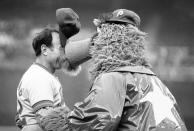 FILE - New York Mets coach Joe Pignatano's cap stands on end as he is "kissed" by the Philadelphia Phillies mascot, the Philly Phanatic, before a baseball game in Philadelphia, June 4, 1981. Pignatano, who made his major league debut with the Brooklyn Dodgers in 1957 and later was a coach for the Mets, died Monday, May 23, 2022, in Naples, Fla. (AP Photo/Rusty Kennedy, File)
