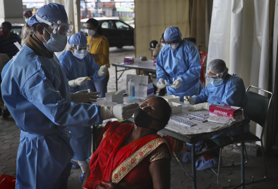Health workers conduct COVID-19 antigen tests for migrant workers in New Delhi, India, Aug. 18, 2020. In June, India began using the cheaper, faster but less accurate tests to scale up testing for the coronavirus — a strategy that the U.S. is now considering. (AP Photo/Manish Swarup)