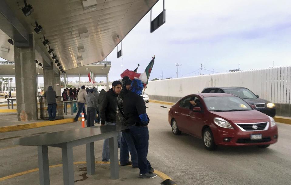 Protesters in Tijuana, Mexico, wave through motorists at the Otay Mesa Port of Entry with San Diego, Calif., after Mexican authorities abandoned their posts on Sunday, Jan. 22, 2017. Protesters took control of vehicle lanes at one of the busiest crossings on the U.S. border Sunday to oppose Mexican gasoline price hikes, waving through motorists into Mexico after Mexican authorities abandoned their posts. (AP Photo/Elliot Spagat)