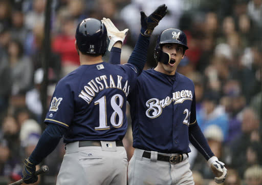 Milwaukee Brewers’ Mike Moustakas, left, congratulates Christian Yelich after Yelich scored on a ground ball hit by Travis Shaw against the Colorado Rockies in the first inning of Game 3 of a baseball National League Division Series, Sunday, Oct. 7, 2018, in Denver. (AP Photo/Joe Mahoney)