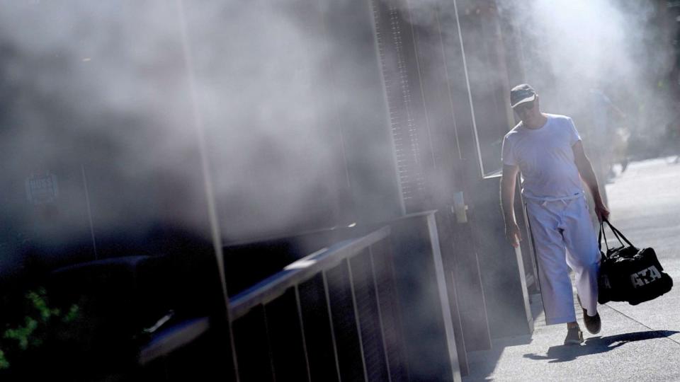 PHOTO: A man walks along a sidewalk under the misters, July 14, 2023, in downtown Phoenix. (Matt York/AP)