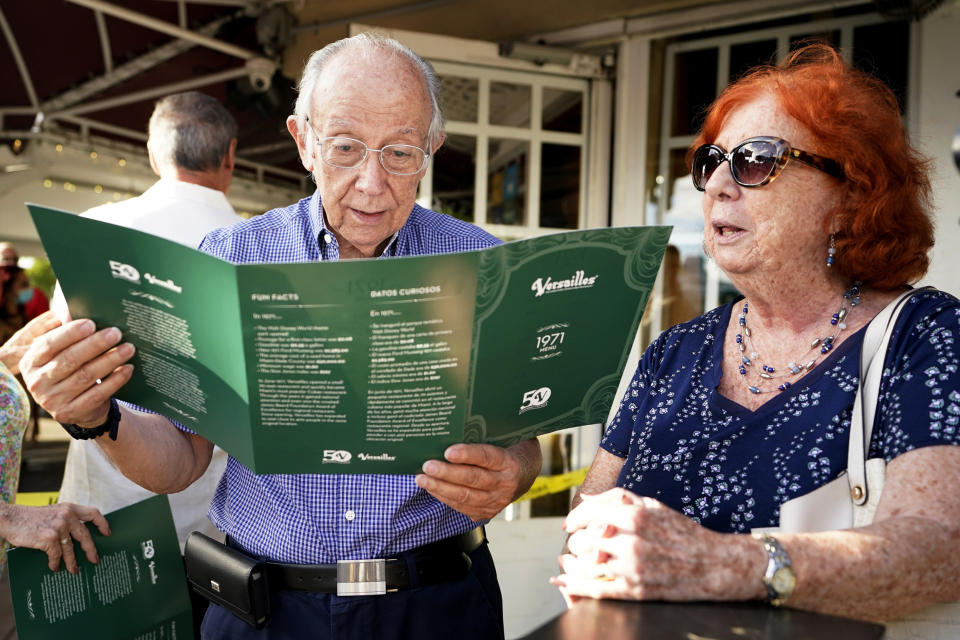 Miguel Suarez, left, reads a replica menu from 1971 before dining with his wife Yolanda at Versailles Restaurant, as the restaurant celebrates its 50th anniversary, on Nov. 10, 2021, in Miami. (Lynne Sladky / AP file)