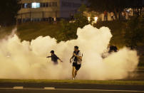 Protesters run through smoke during a protest after the Belarusian presidential election in Minsk, Belarus, Sunday, Aug. 9, 2020. Police and protesters clashed in Belarus' capital and the major city of Brest on Sunday after the presidential election in which the authoritarian leader who has ruled for a quarter-century sought a sixth term in office. (AP Photo/Sergei Grits)