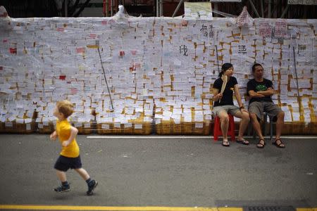 Protesters sit in front of a wall covered with messages, as they block an area around the government headquarters in Hong Kong October 2, 2014. REUTERS/Carlos Barria