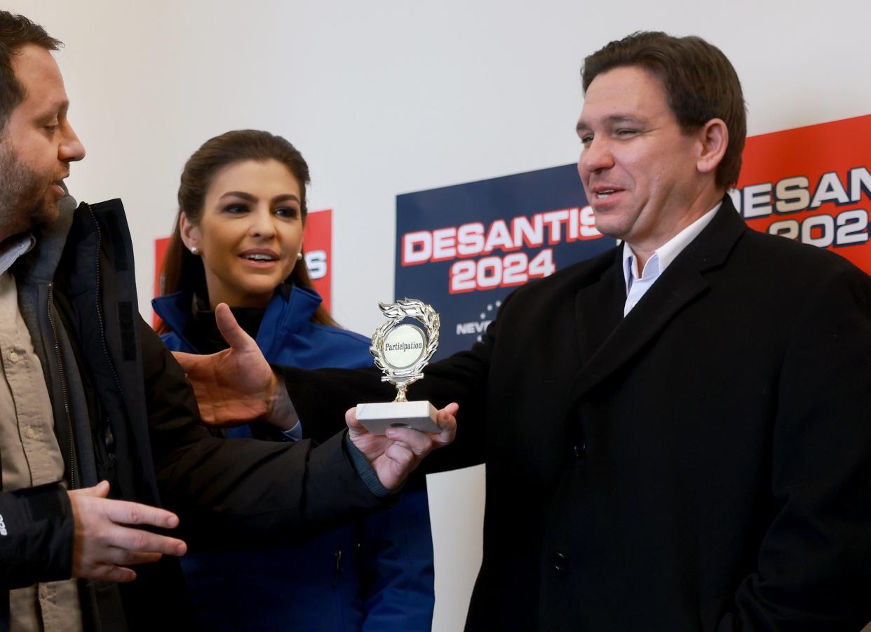 A member of comedy duo "The Good Liars" tries to give Republican presidential candidate Florida Gov. Ron DeSantis a 'participation trophy' during a campaign stop on Jan. 13, 2024, in Atlantic, Iowa. DeSantis did not take the trophy and the comedians were escorted out of the room. Iowa Republicans will be the first to select their party's nomination for the 2024 presidential race when they caucus on Jan. 15, 2024.