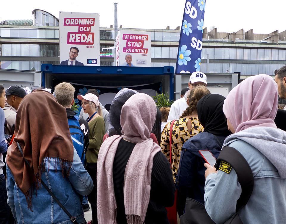 In this Aug. 31, 2018 photo young women listen to a party member of the right wing Sweden Democrats in Stockholm, Sweden. (AP Photo/Michael Probst)