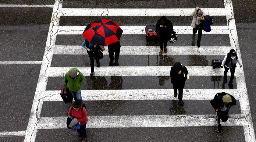 EL SEGUNDO-CA-JANUARY 22, 2024: Travelers arrive at LAX in the rain on January 22, 2024. The strongest in a series of three storms is sliding into the Southland today. (Christina House / Los Angeles Times)