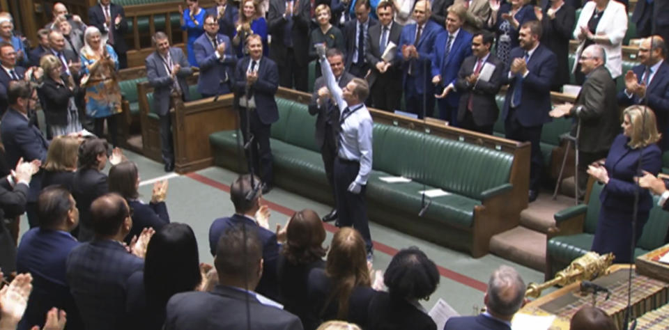 Craig Mackinlay, Conservative MP for South Thanet, is applauded by members of parliament as he returns to the House of Commons for the first time since he was rushed into hospital with sepsis on September 28, which left him with both of his hands and feet amputated, at the Parliament in London, Wednesday May 22, 2024. (House of Commons/UK Parliament via AP)