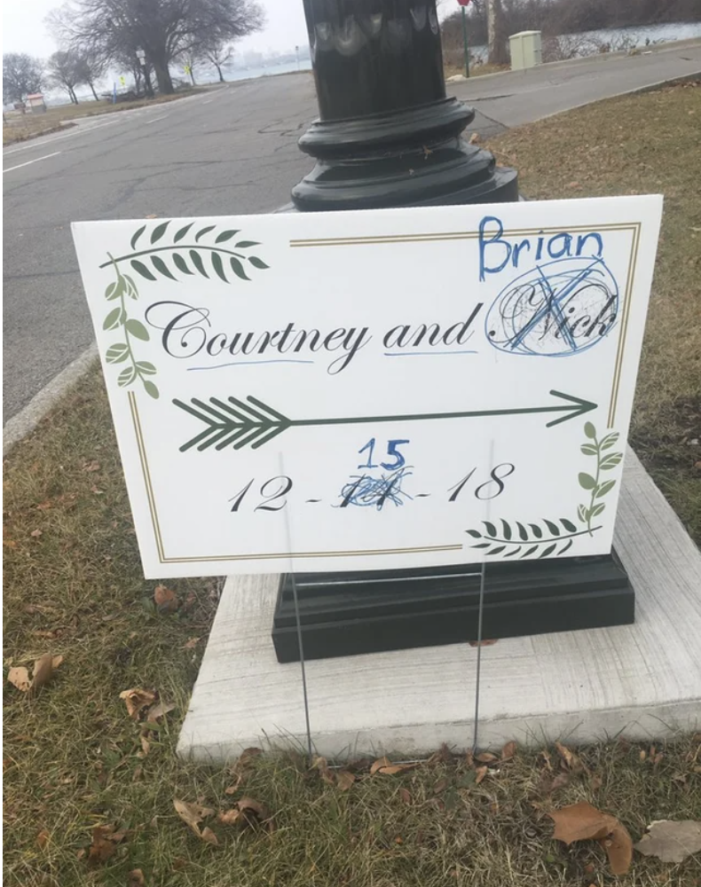 A sign for a wedding has the groom's name crossed out and replaced, as well as the date rewritten from the 11th to the 15th