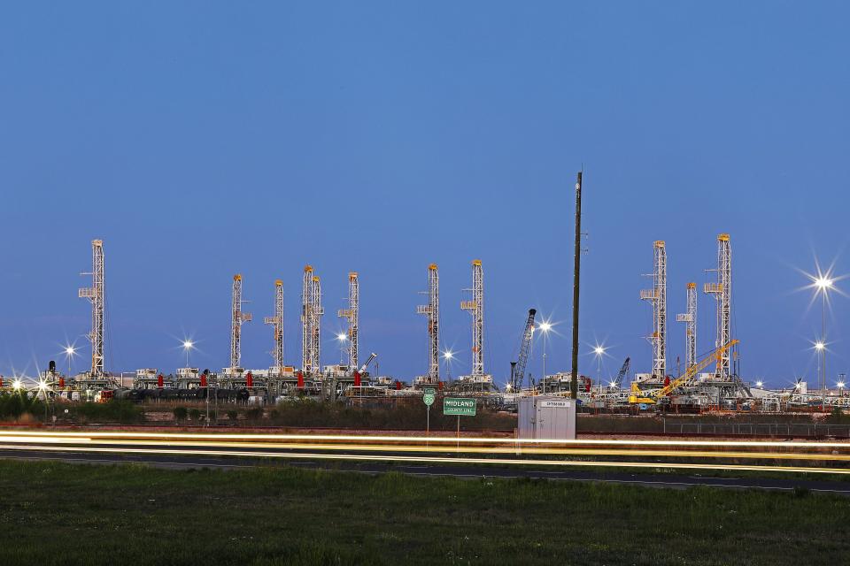 In this Thursday evening, April 2, 2020 photo, traffic passes over the Midland-Odessa county line in front of an oil rig storage yard. (Odessa American/Eli Hartman)