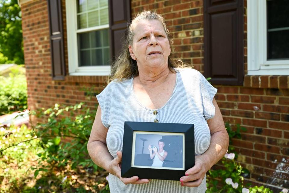 Dawn Dusharm, 59, holds a photo of her son, Justin Ervin, at her home in Charlotte, NC. Justin was shot and killed in 2005 outside of a convenience store on Glenwood Drive trying to protect his girlfriend from three young men who’d attacked her. “I just got a phone call and they told me he was dead,” Dusharm said. “I didn’t believe it.” nearly 20 years later, she’s still waiting for someone to be held accountable for her son’s death.