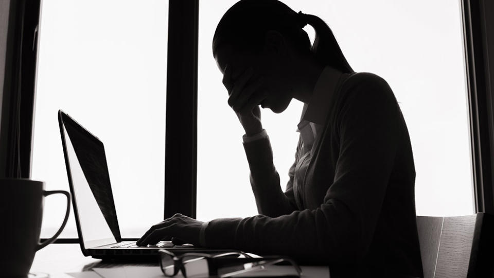 Picture of a silhouette of a woman, looking at. her laptop. Image based abuse reports have risen amid the coronavirus lockdown