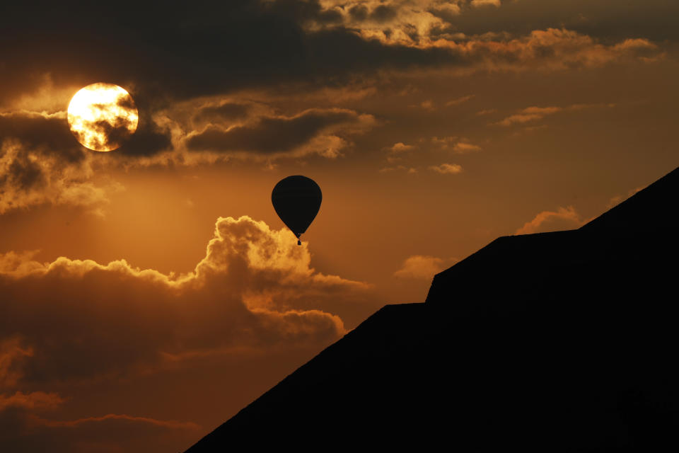 In this Thursday, March 21, 2019 photo, a balloon flies near the Pyramid of the Sun as the sun rises in Teotihuacan, Mexico, on the Spring equinox. (AP Photo/Marco Ugarte)