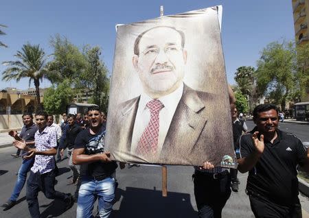 Iraqis carry a portrait of Iraqi Prime Minister Nuri al-Maliki as they march in support of him in Baghdad, August 11, 2014. REUTERS/Ahmed Saad