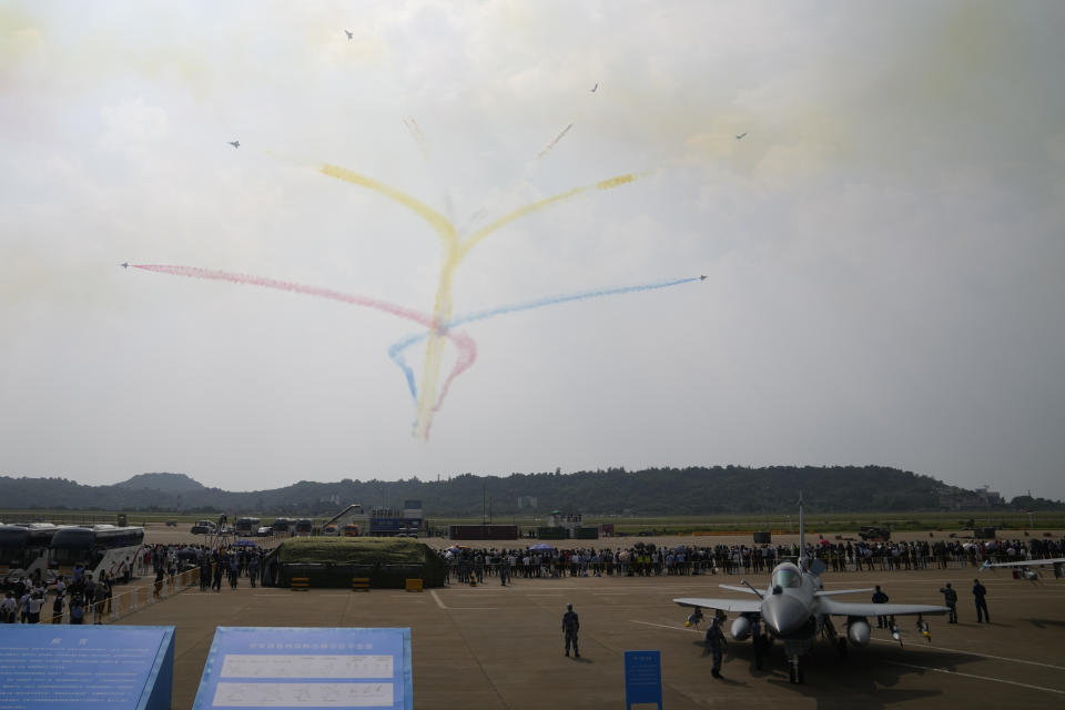 Members of the "August 1st" Aerobatic Team of the Chinese People's Liberation Army (PLA) Air Force perform near the J-10C on display during the 13th China International Aviation and Aerospace Exhibition, also known as Airshow China 2021, on Tuesday, Sept. 28, 2021 in Zhuhai in southern China's Guangdong province. (AP Photo/Ng Han Guan)