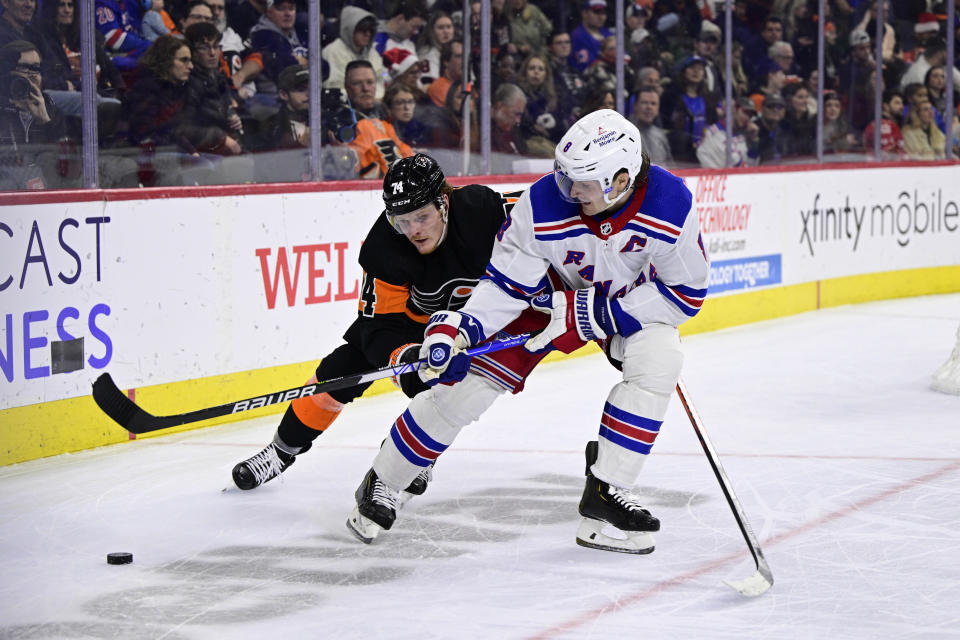 New York Rangers' Jacob Trouba, right, and Philadelphia Flyers' Owen Tippett battle for the puck during the second period of an NHL hockey game, Saturday, Dec. 17, 2022, in Philadelphia. (AP Photo/Derik Hamilton)
