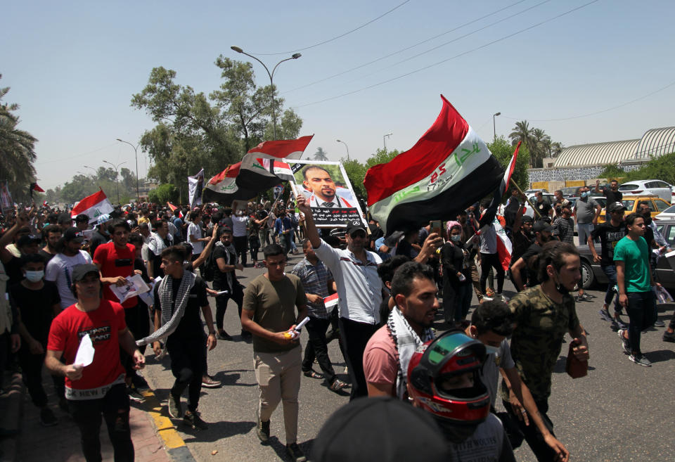 Anti-government protesters chant slogans as they hold posters of slain activist Ehab Wazni outside the Green Zone area which houses the seat of the country's government and foreign embassies, in Baghdad, Iraq, Tuesday, May 25, 2021. Hundreds of Iraqi protesters have taken to the streets of Baghdad to decry a recent spike in assassinations targeting outspoken activists and journalists. (AP Photo/Khalid Mohammed)