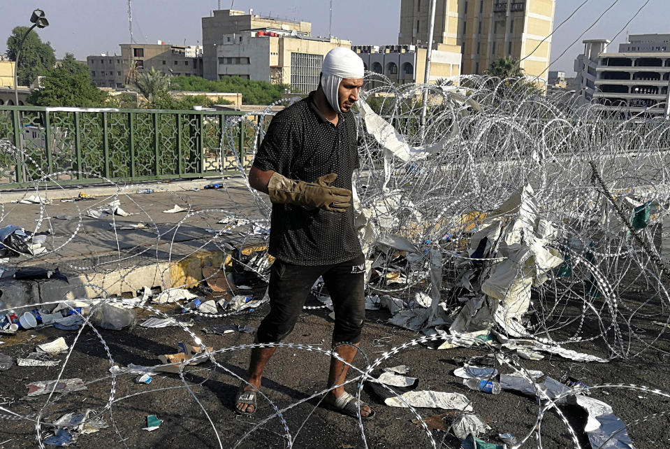 A wounded protester prepares to remove the barbed wire set by security forces to close the Al-Sanak Bridge leading to the Green Zone during a demonstration in Baghdad, Iraq, Thursday, Oct. 31, 2019. Late Wednesday, hundreds of people headed to the Al-Sanak Bridge that runs parallel to the Joumhouriya Bridge, opening a new front in their attempts to cross the Tigris River to the Green Zone. Security forces fired volleys of tear gas that billowed smoke and covered the night sky. (AP Photo/Khalid Mohammed)