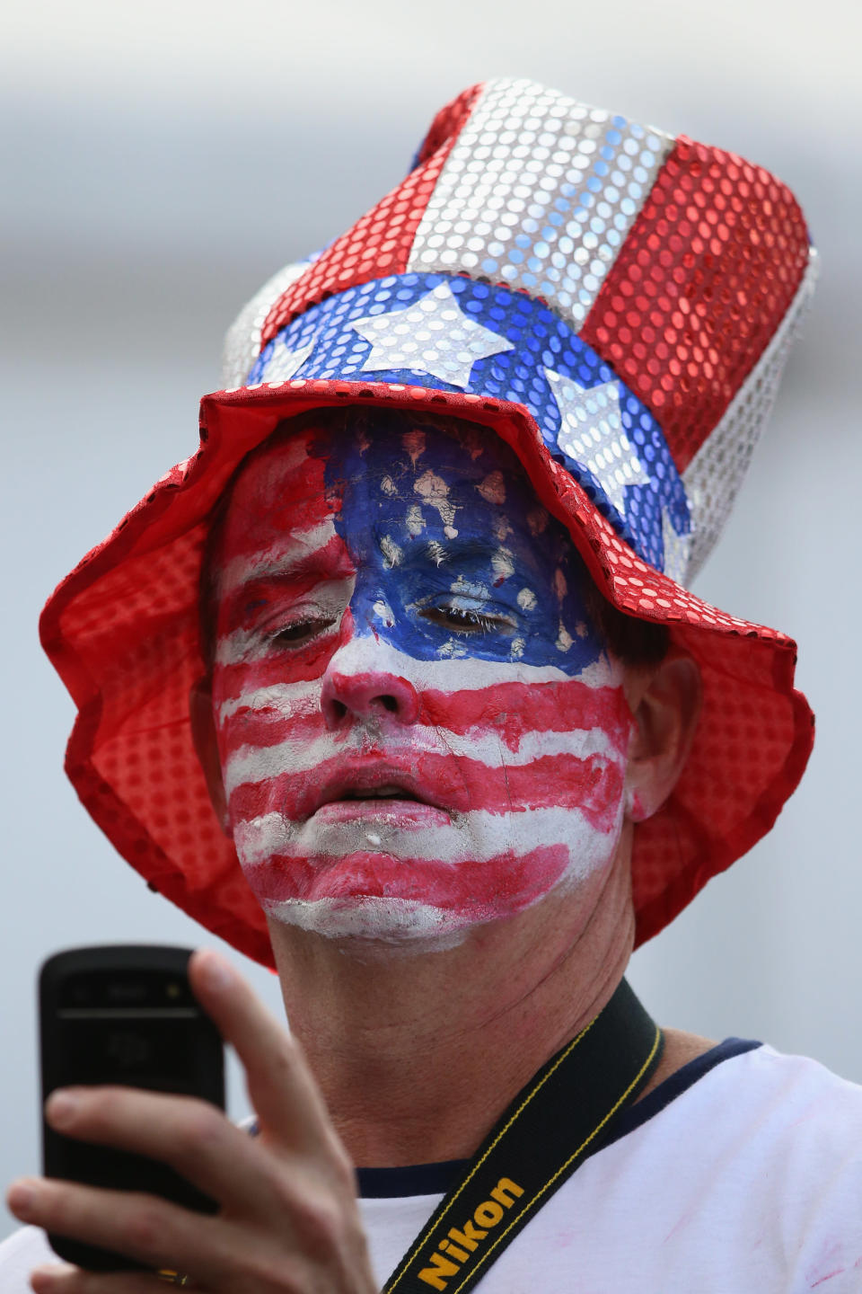 LONDON, ENGLAND - JULY 29: A man with an American flag painted on his face takes a photograph on his phone at the Olympic Park on Day 2 of the London 2012 Olympic Games on July 29, 2012 in London, England. (Photo by Jeff J Mitchell/Getty Images)