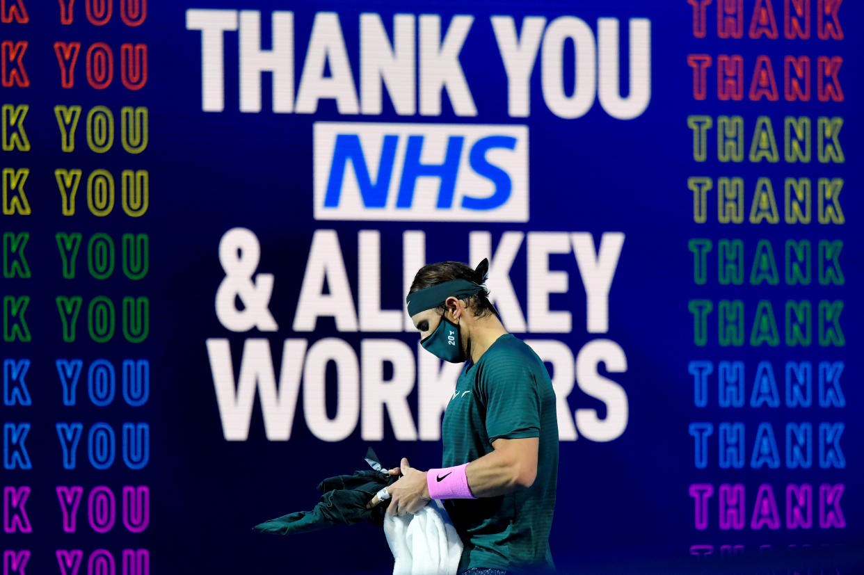 Tennis - ATP Finals - The O2, London, Britain - November 19, 2020  Spain's Rafael Nadal wearing a mask infront of a thank you message to the NHS and key workers as he waits for the start of the second set during his group stage match against Greece's Stefanos Tsitsipas  REUTERS/Toby Melville