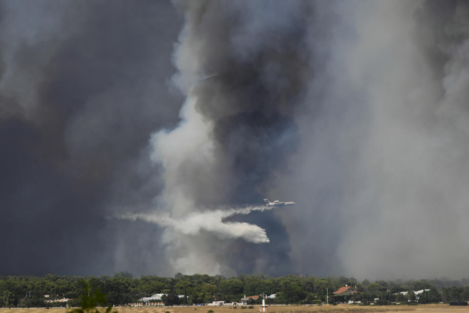 An airplane drops water during a wildfire that broke out in Tatoi, northern Athens, Greece, Tuesday, Aug. 3, 2021. The Greek Fire Service maintained an alert for most of the country Tuesday and Wednesday, while public and some private services shifted operating hours to allow for afternoon closures. (AP Photo/Michael Varaklas)
