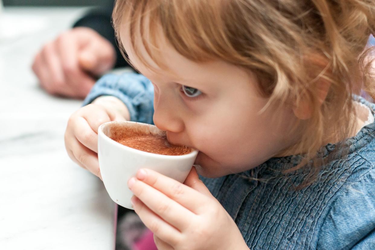 little girl drinking latte from cup