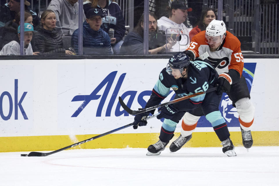 Seattle Kraken right wing Kailer Yamamoto (56) tries to control the puck under pressure from Philadelphia Flyers defenseman Rasmus Ristolainen (55) during the second period of an NHL hockey game, Friday, Dec. 29, 2023, in Seattle. (AP Photo/John Froschauer)