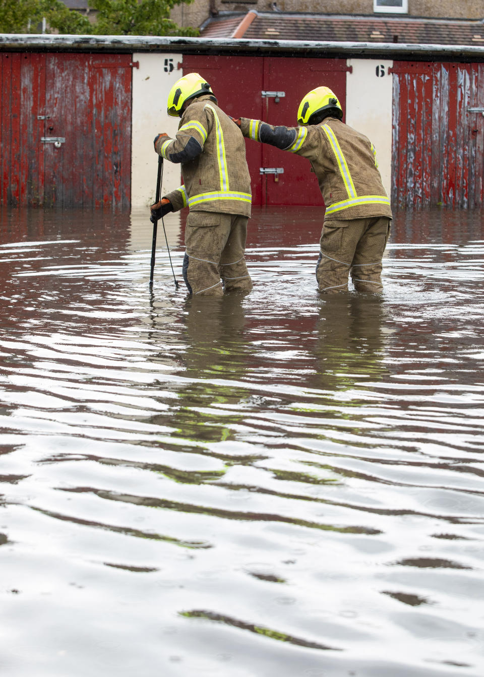 Fire brigade officers look for a blocked drain which has flooded a car park leaving one car flooded in Barnton, Edinburgh, as heavy rains hits most of the country