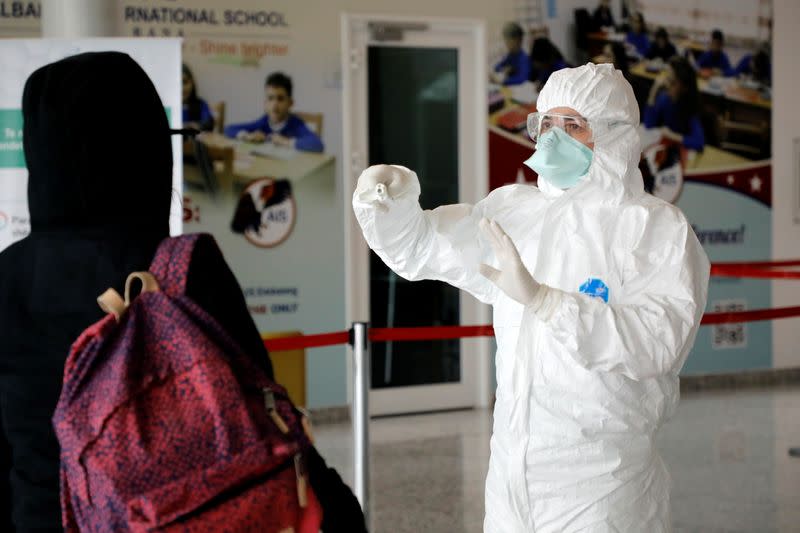 Medical staff member, wearing protective suit, gestures at Tirana International Airport