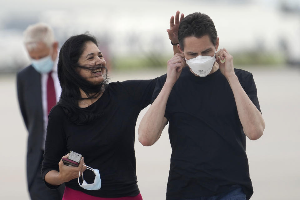 Michael Kovrig, centre right, puts on a facemask as his wife Vina Nadjibulla, center left, walks with him after his arrival at Pearson International Airport in Toronto, Saturday, Sept. 25, 2021. China, the U.S. and Canada completed a high-stakes prisoner swap Saturday with joyous homecomings for Kovrig and Michael Spavor, two Canadians held by China and for an executive of Chinese global communications giant Huawei Technologies charged with fraud. (Frank Gunn /The Canadian Press via AP)