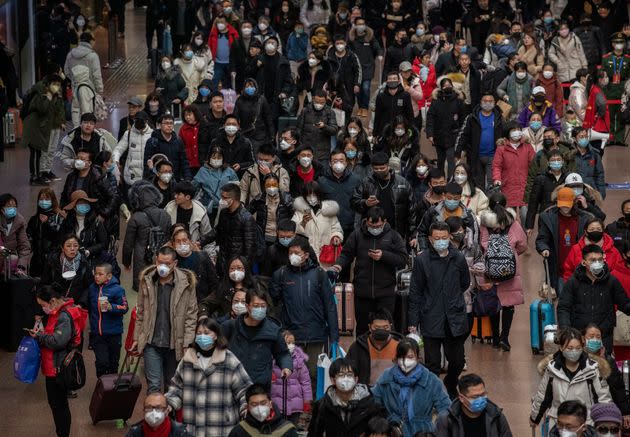 Chinese passengers, most wearing masks, arrive to board trains before the annual Spring Festival at a Beijing railway station. 