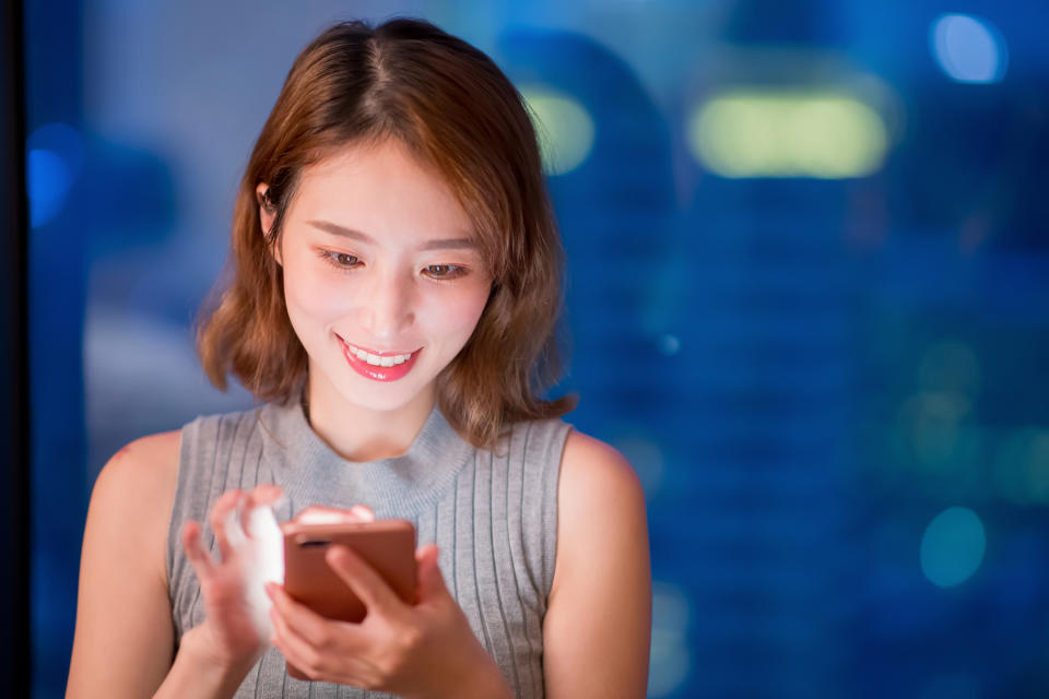 A young woman plays a game on her smartphone.