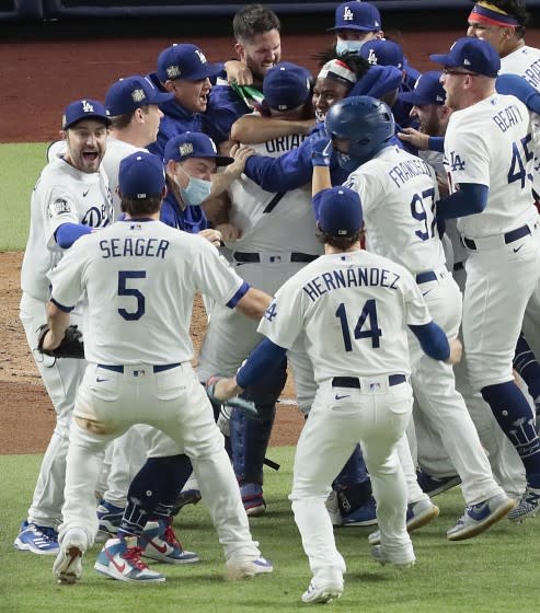 Arlington, Texas, Tuesday, October 27, 2020 Los Angeles Dodgers starting pitcher Julio Urias (7) is mobbed by teammates after closing to a 3-1 win over the Rays to clinch the World Series at Globe Life Field. (Robert Gauthier/ Los Angeles Times)