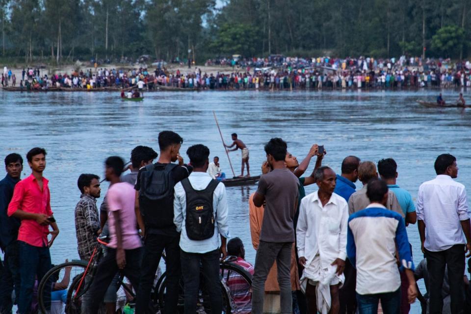 In this picture taken on 25 September 2022, people gather along the banks of the Karatoa river after a boat capsized near the town of Boda (AFP via Getty Images)