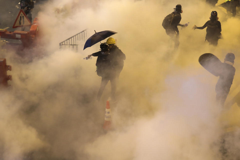 Protesters react from tear gas fired by riot policemen during the anti-extradition bill protest at Causeway Bay in Hong Kong, Sunday, Aug. 4, 2019. The first of two planned protests in Hong Kong on Sunday has kicked off from a public park just hours after police said they arrested more than 20 people for unlawful assembly and other offences during the previous night's demonstrations. (AP Photo/Vincent Thian)