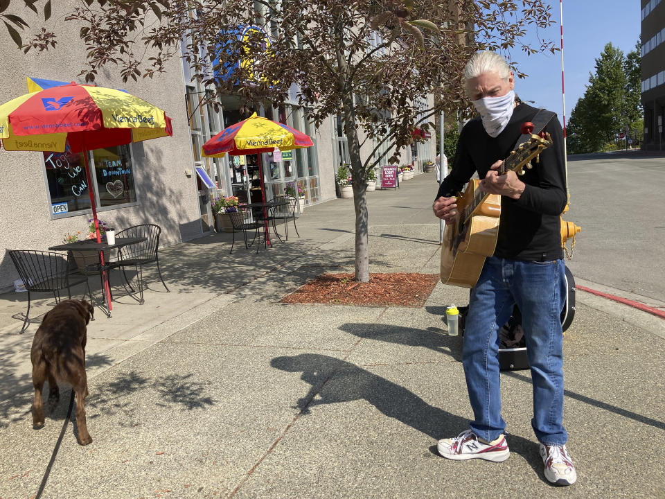 Street musician Cal Austermuhl performs on a street in downtown Anchorage, Alaska Wednesday, July 1, 2020, the same day Alaska residents began receiving their share of the state's oil wealth. Austermuhl says his $992 share was already spent on bills. (AP Photo/Mark Thiessen)