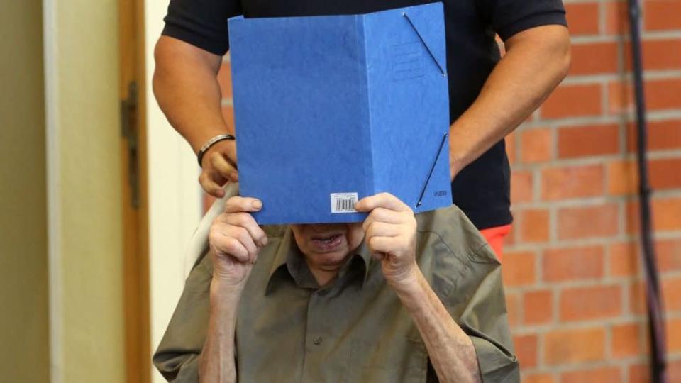 El exguardia nazi Josef S esconde su cara detrás de un folder, durante el juicio en Brandenburg an der Havel, 28 de junio, 2022
