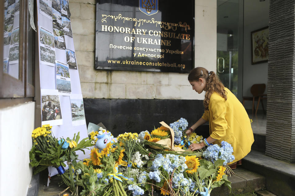 A Ukrainian national places flowers to pay tribute to people killed in Russia's war against Ukraine to mark the one-year anniversary of Russia's invasion of Ukraine, at Ukraine consulate in Bali, Indonesia on Friday, Feb. 24, 2023. (AP Photo/Firdia Lisnawati)