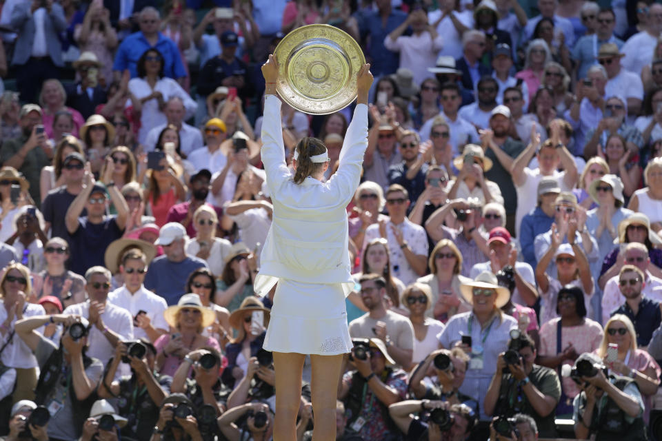 Kazakhstan's Elena Rybakina holds the trophy as she celebrates after beating Tunisia's Ons Jabeur to win the final of the women's singles on day thirteen of the Wimbledon tennis championships in London, Saturday, July 9, 2022. (AP Photo/Kirsty Wigglesworth)