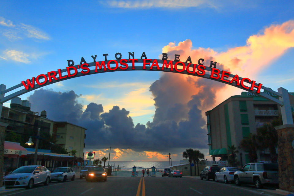 Sunset at Daytona Beach with iconic arch reading "WORLD'S MOST FAMOUS BEACH" over a street leading to the ocean