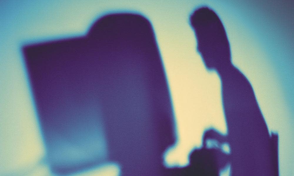 Silhouette of a businessman working on a computer.